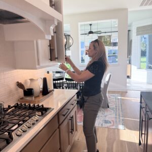 Woman opening upper cabinet in modern kitchen