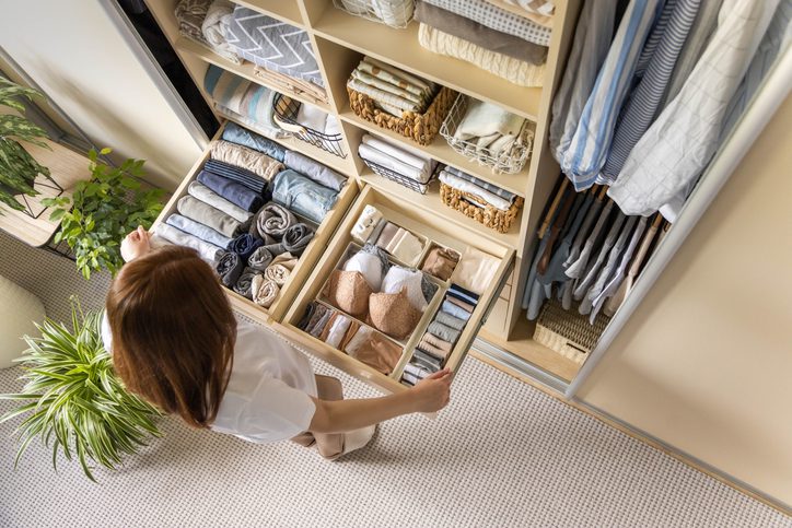 Person organizing folded clothes and closet drawers