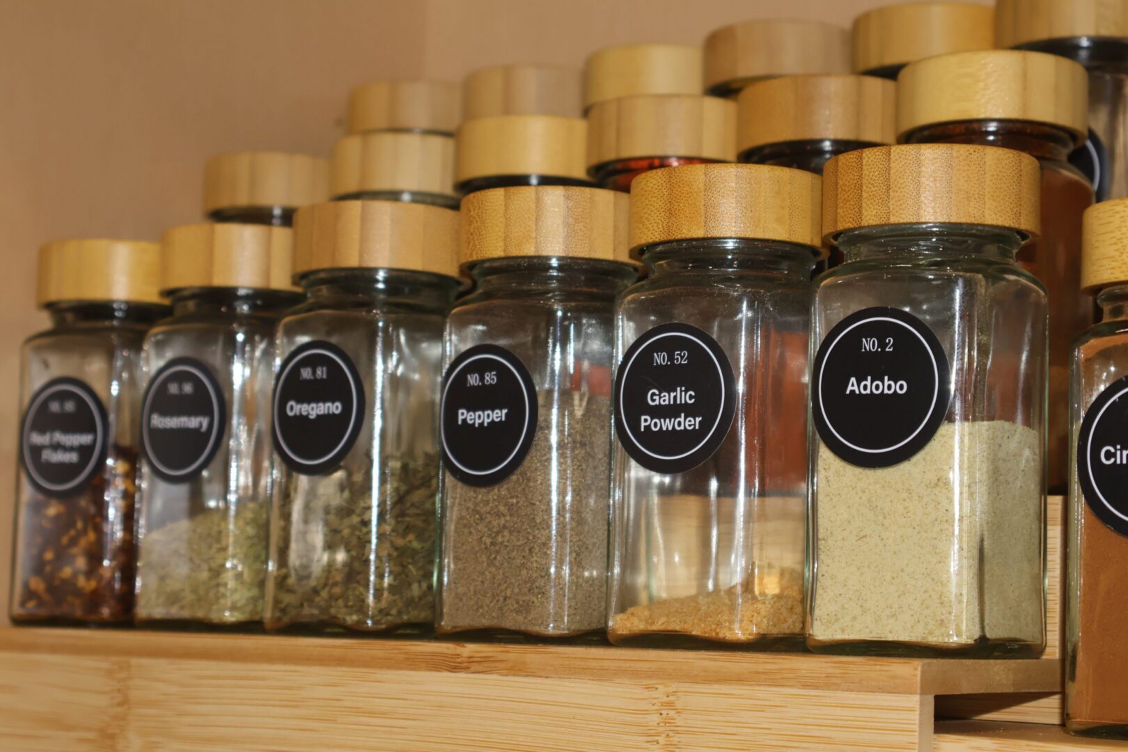 Labeled glass spice jars on wooden shelf